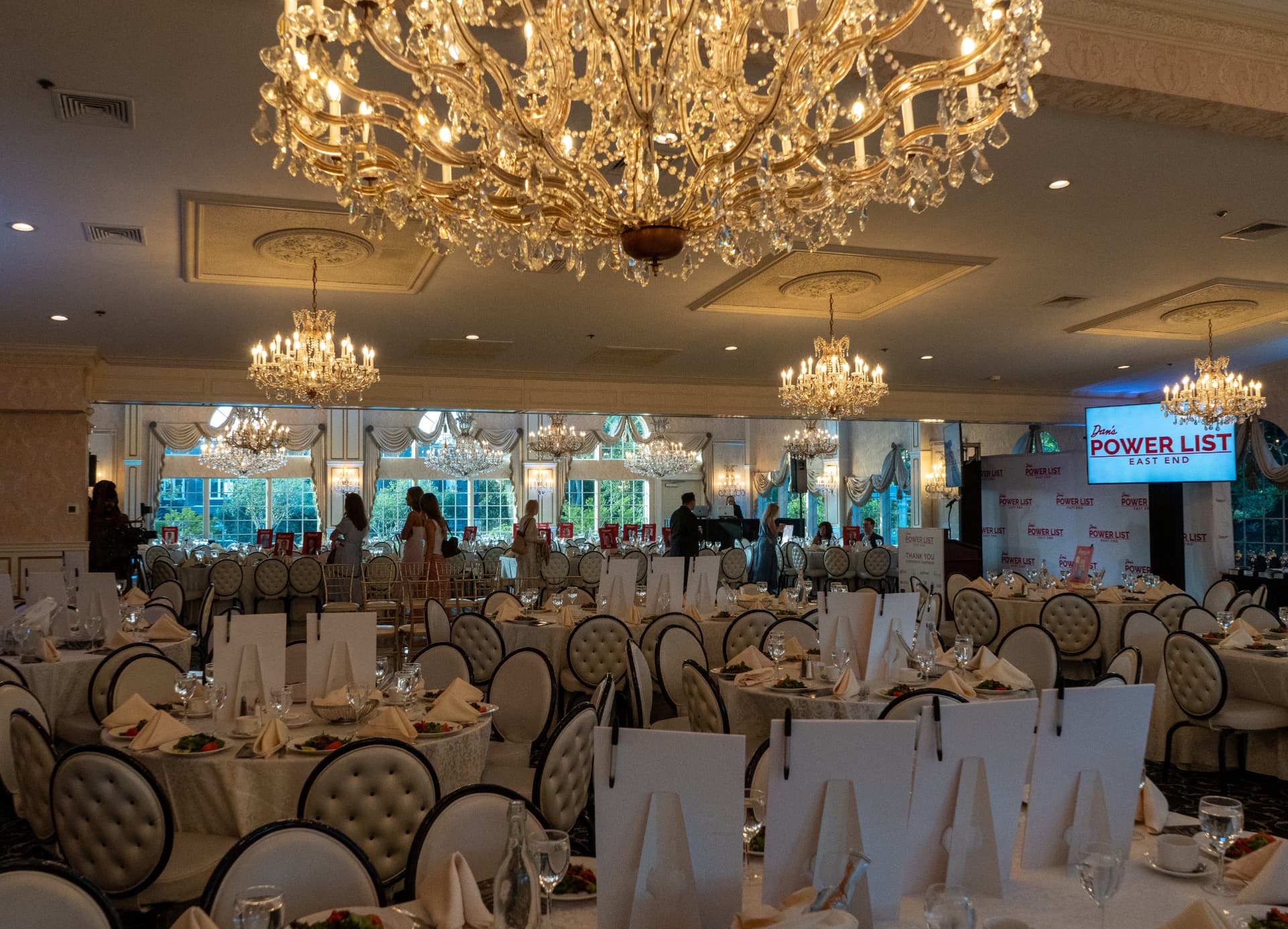 Guests arriving in the chandelier-lit ballroom with the Power List screen glowing at the stage