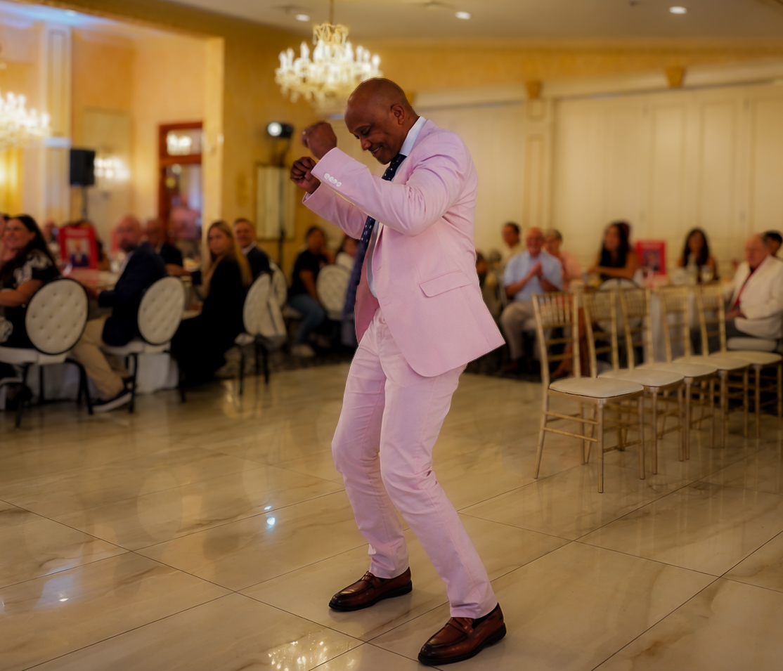 Guest in a pink suit dancing on the marble floor as the room watches