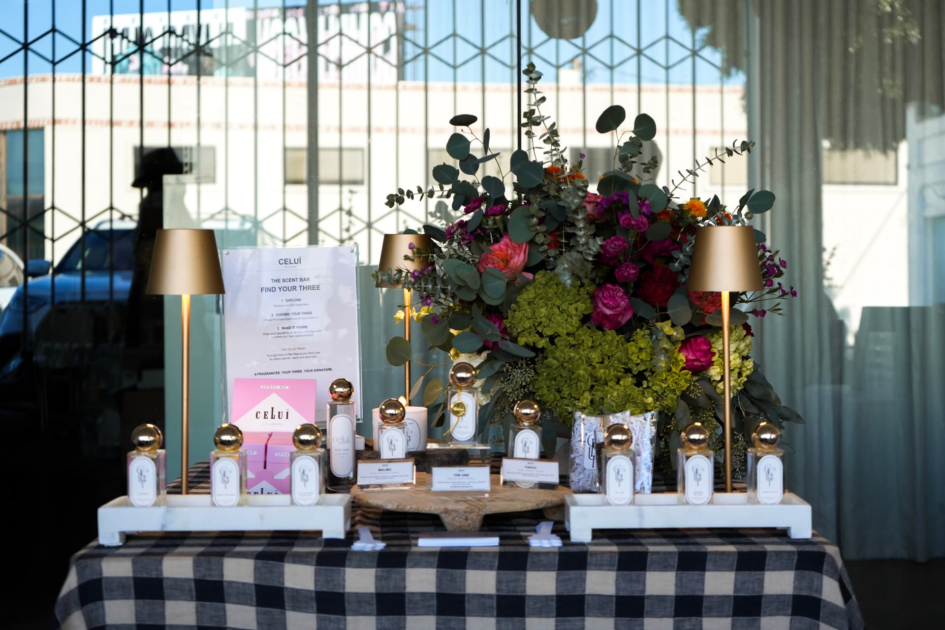 Fragrance bar display with gold lamps and florals at the event