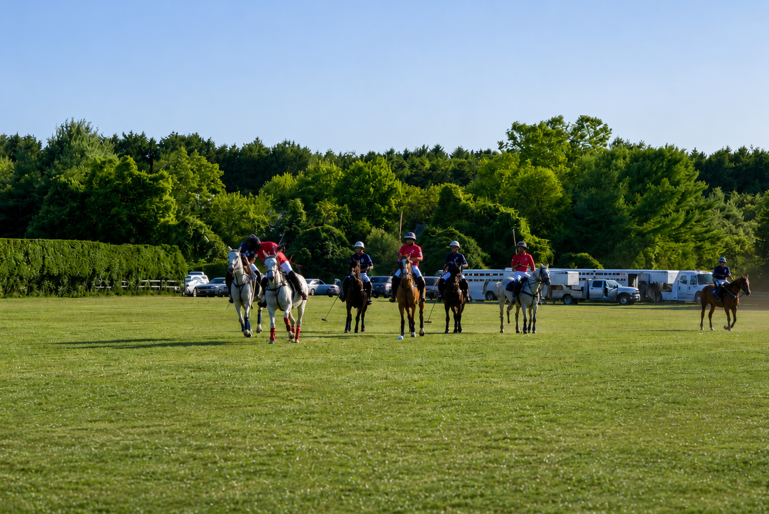 Riders galloping across the open field in late afternoon light