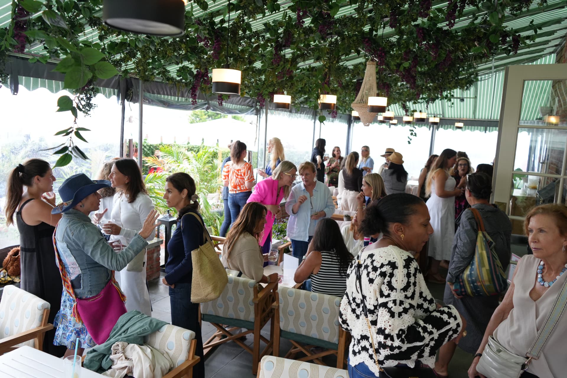 The full room mingling beneath the green striped awning and hanging florals