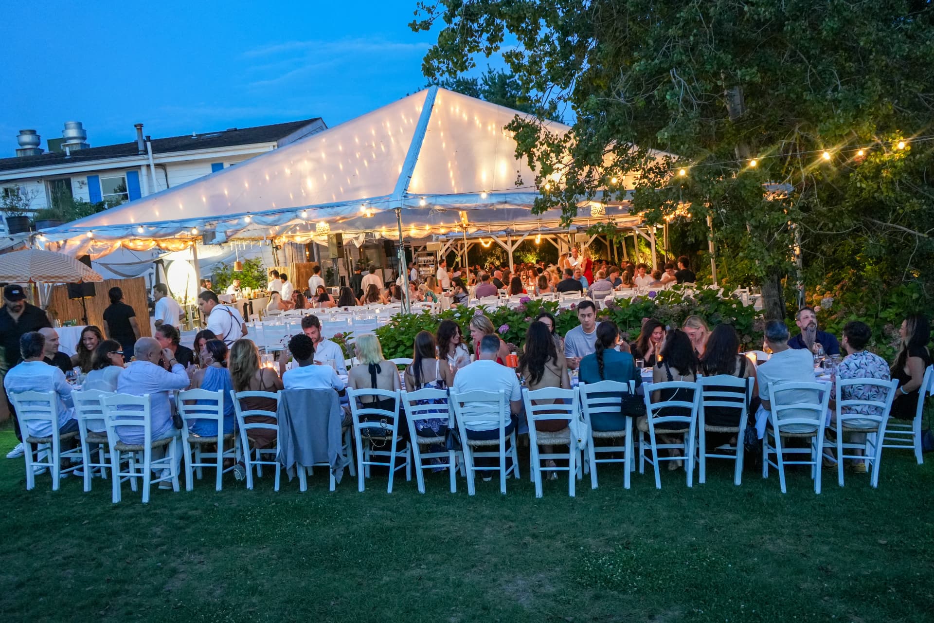 Blue-hour view of the illuminated dinner tent at the Voice of the Planet Hamptons dinner