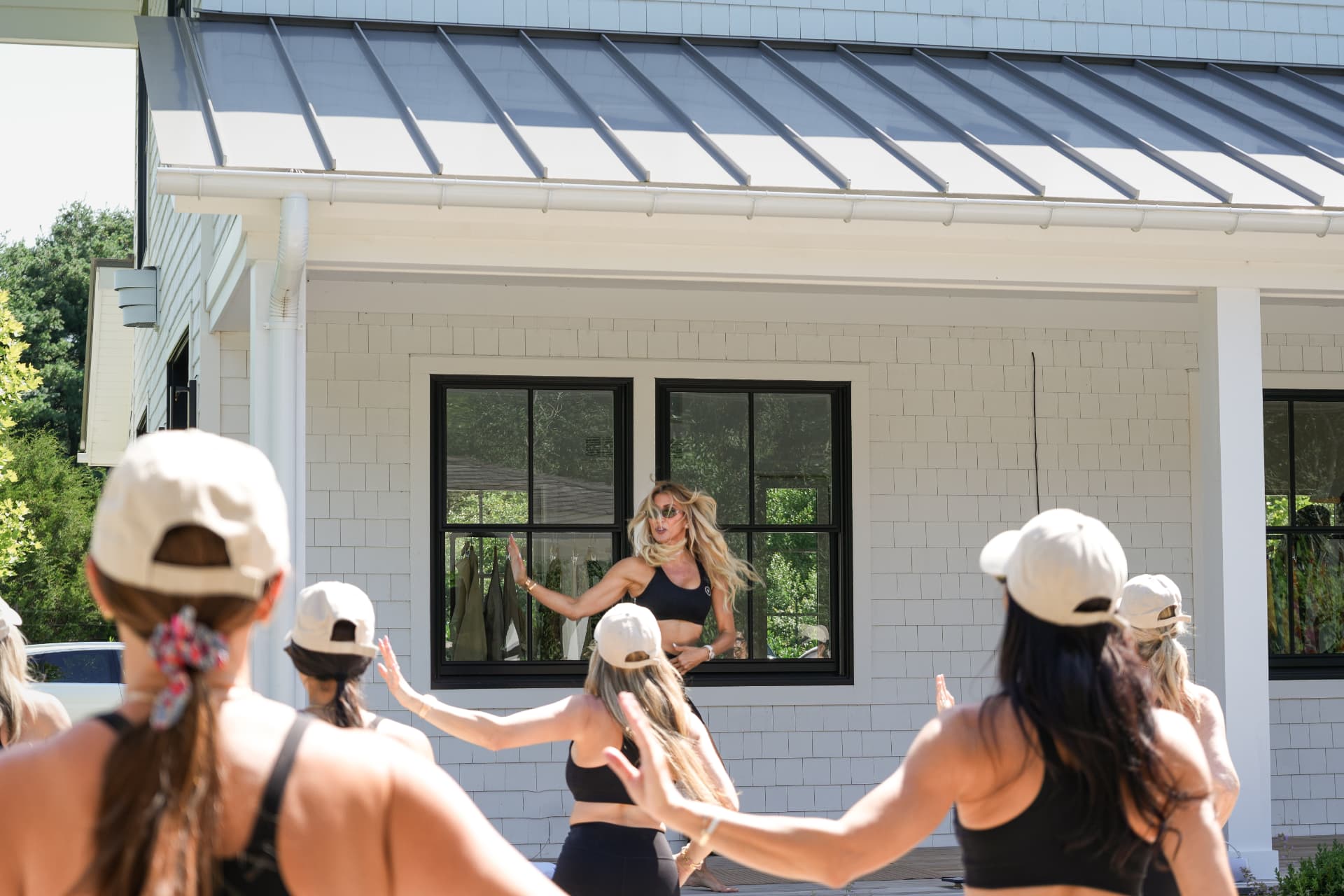 Instructor leading the class from the poolhouse porch as guests follow along