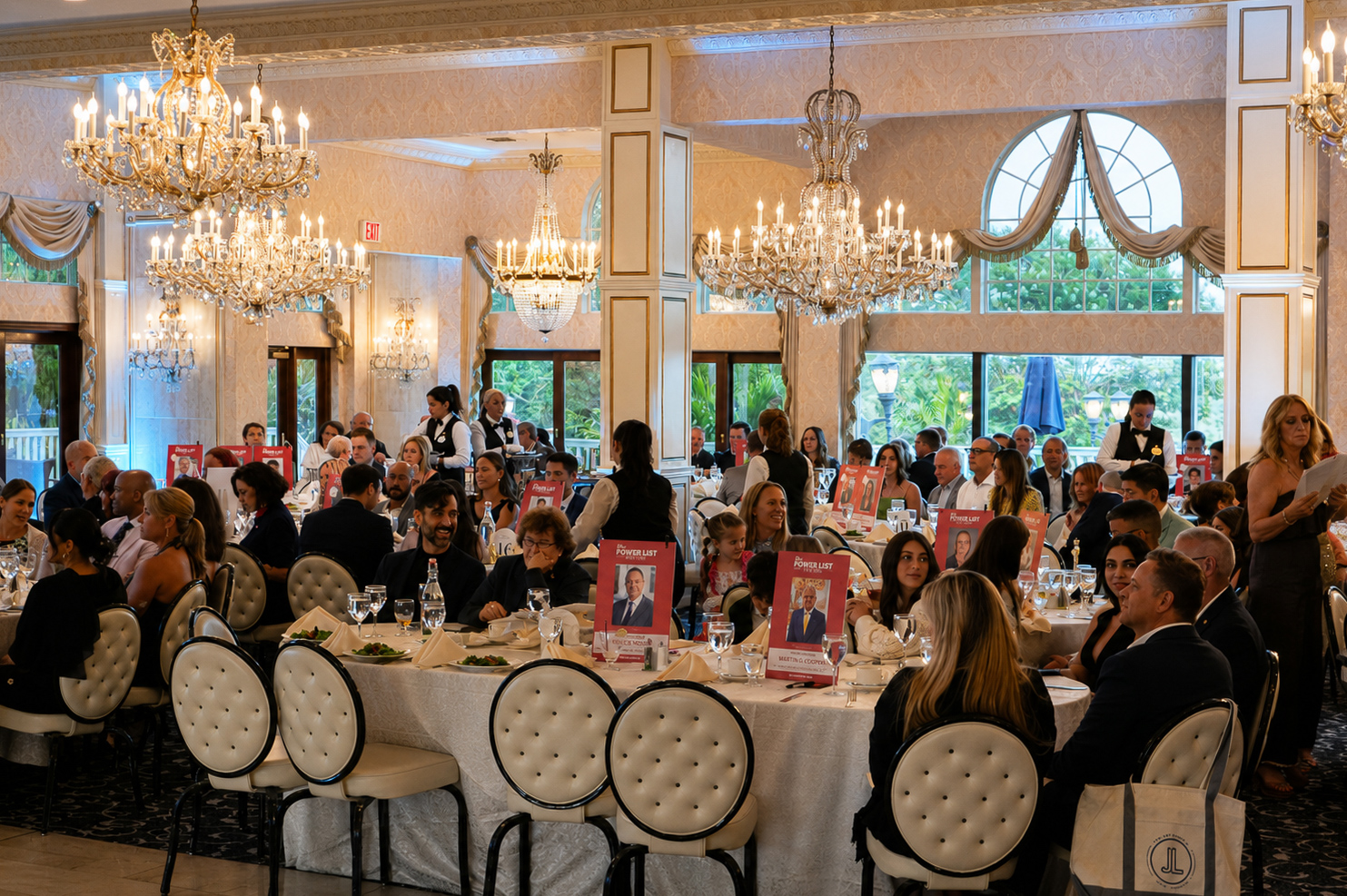 Chandelier-lit ballroom filled with guests and honoree table cards during the luncheon