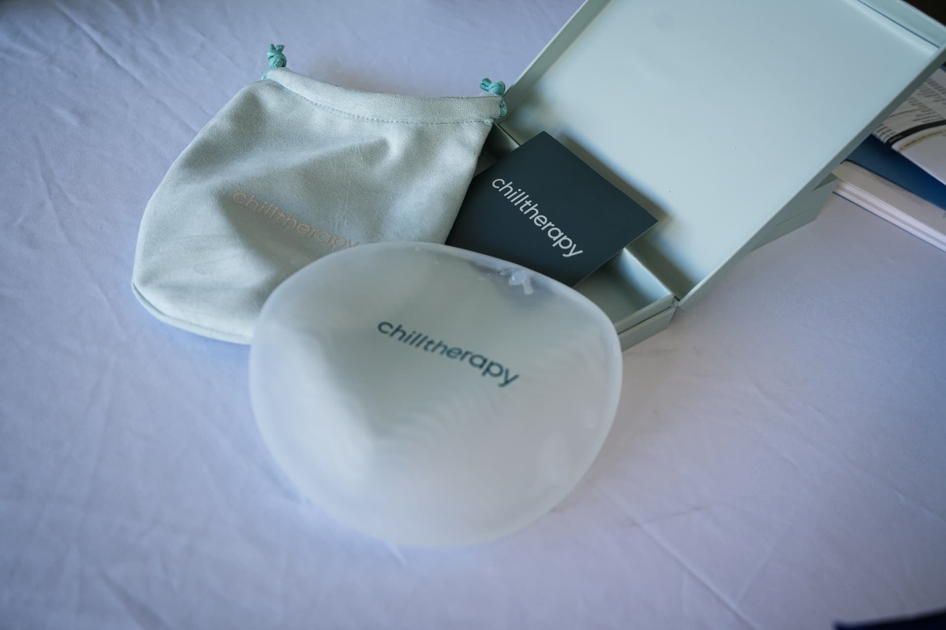 Frosted cooling skincare tool with pouch and gift box on a linen table