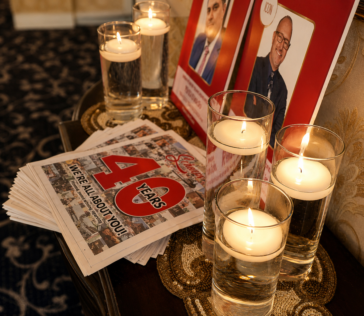 Floating candles and stacked Dan's Papers issues styled beside honoree signage