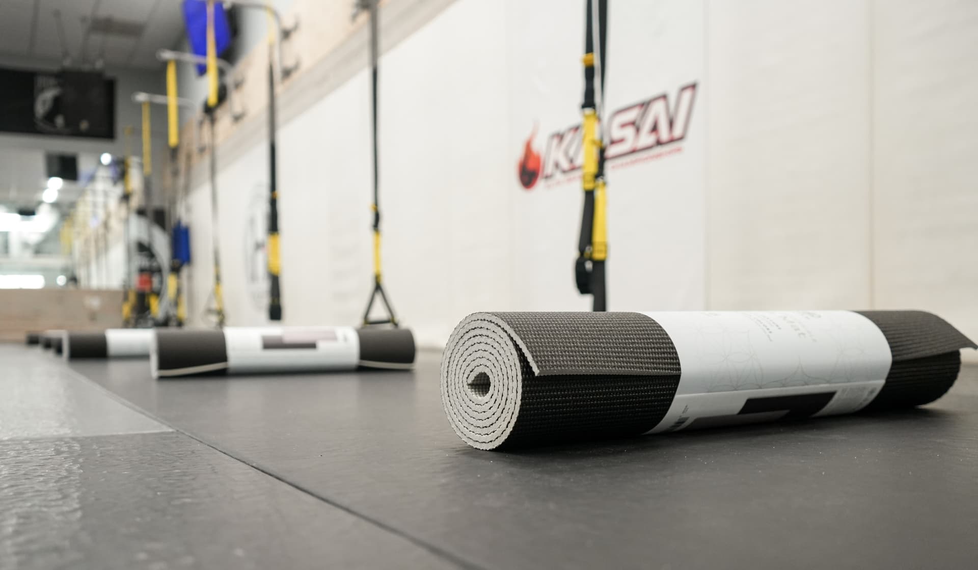 Rolled yoga mats lined along the mat floor before the wellness session