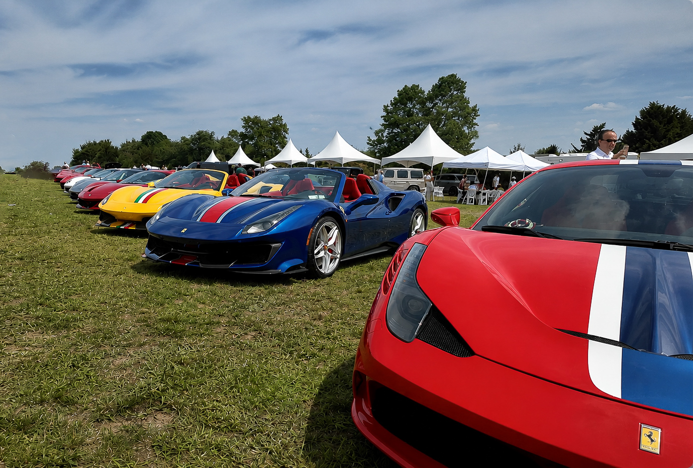 Row of colorful Ferraris across the field with guests looking on