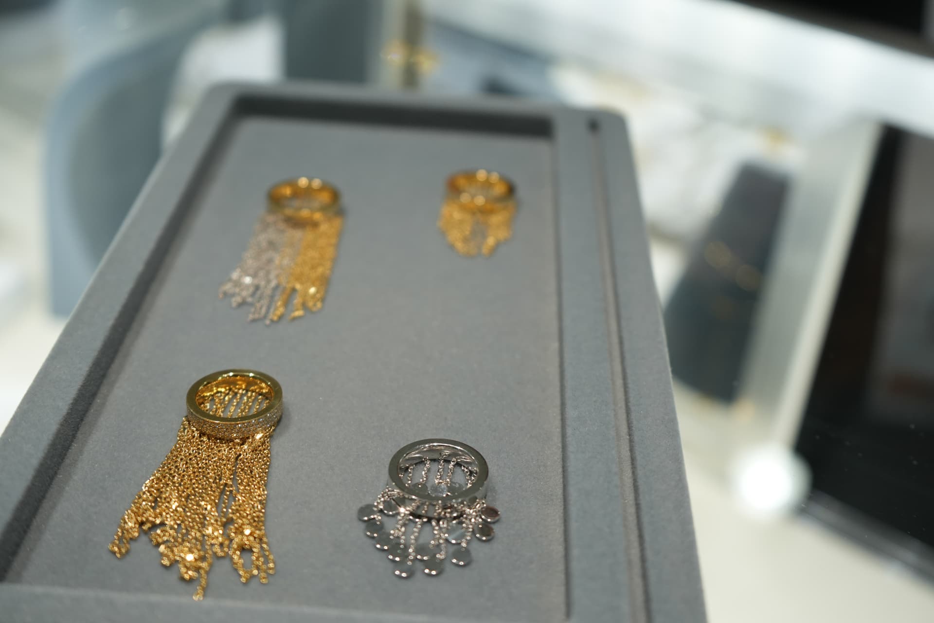 Gold and white-gold fringe cocktail rings arranged on a grey presentation tray