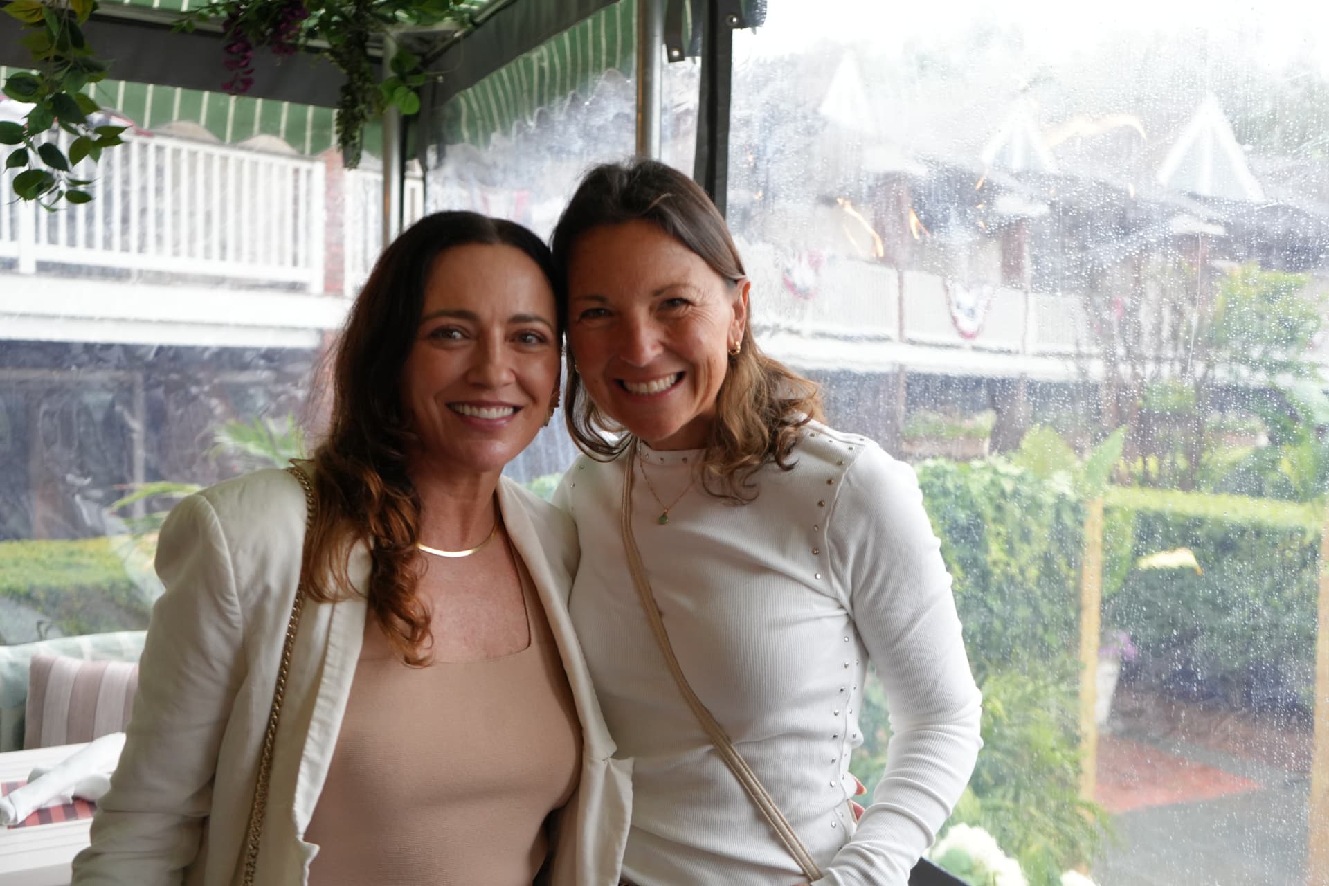 Two guests photographed together beside the rain-flecked garden windows