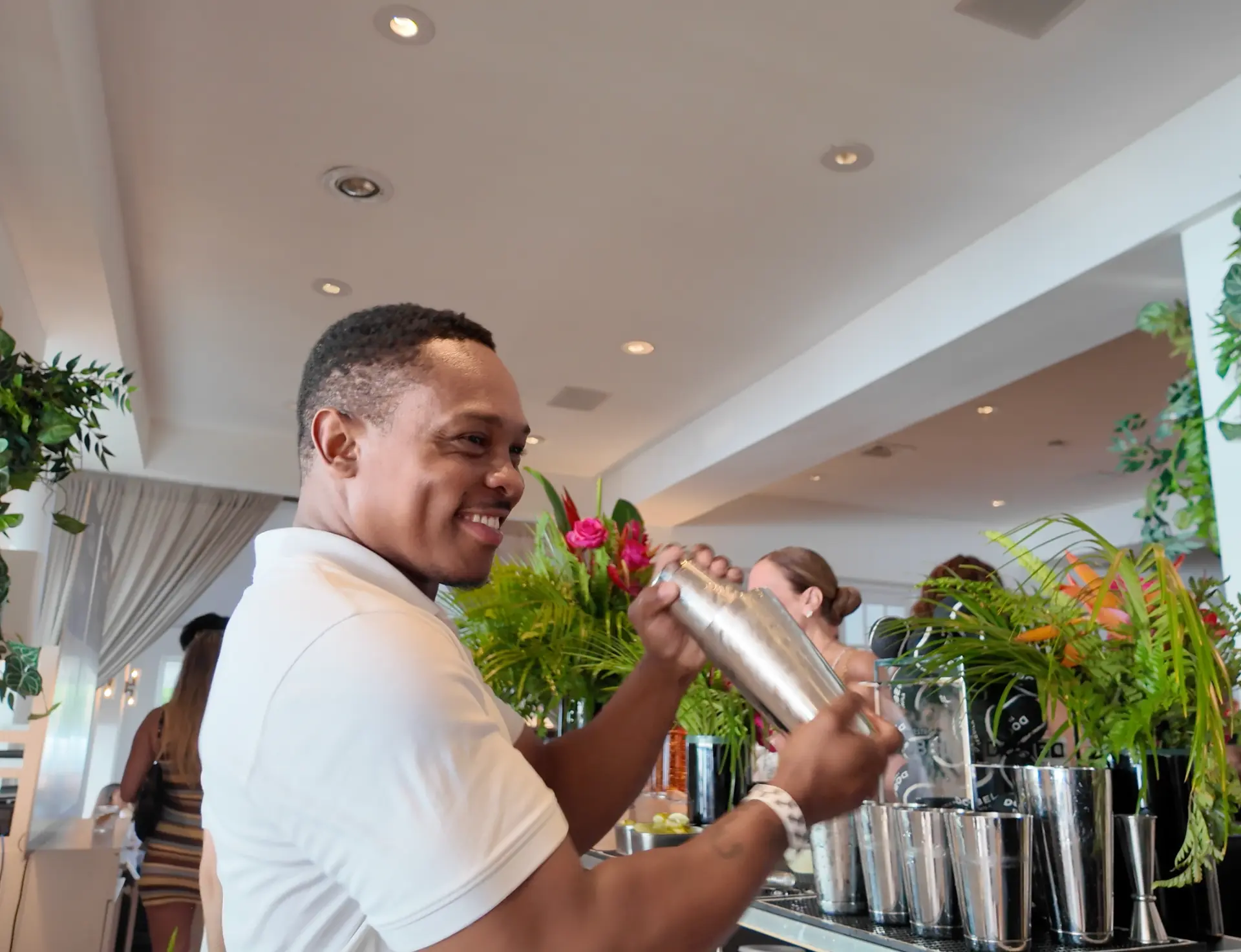 Bartender smiling while shaking a cocktail behind the bar