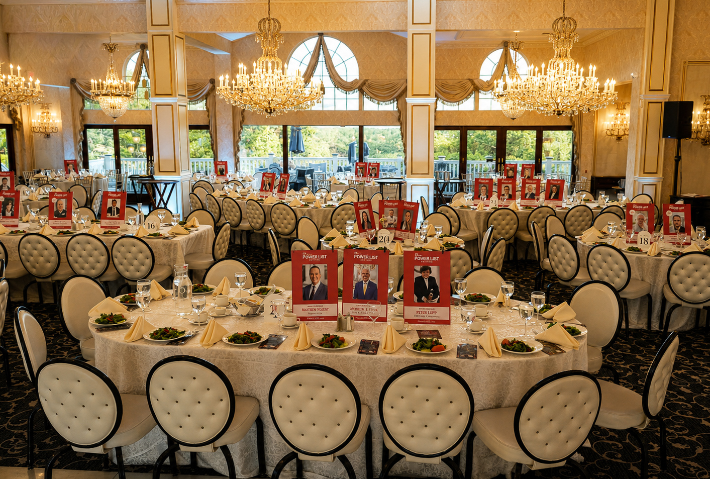 Wide view of the ballroom set with honoree table cards beneath crystal chandeliers