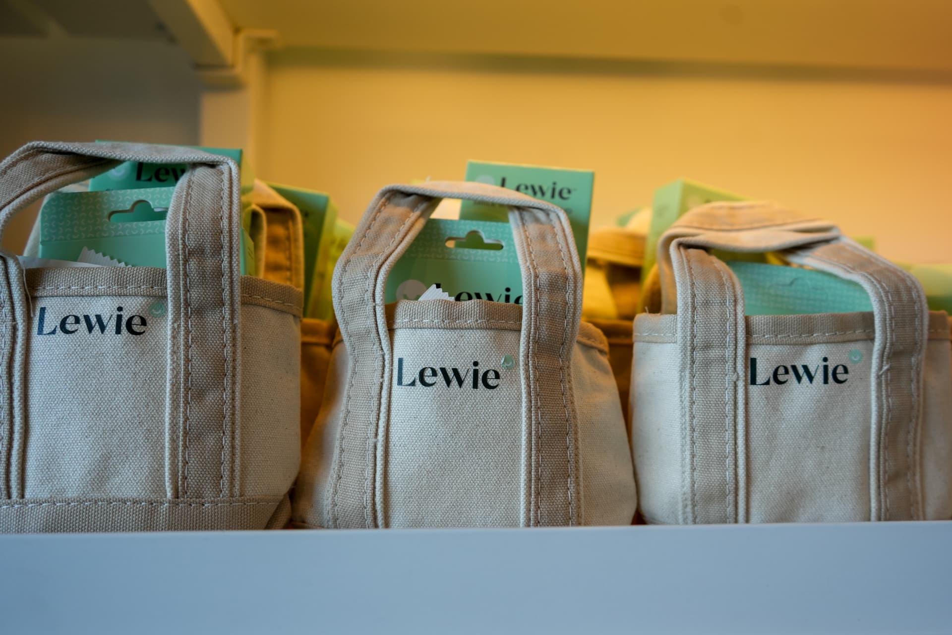 Small canvas gift bags with product cards lined up on a shelf