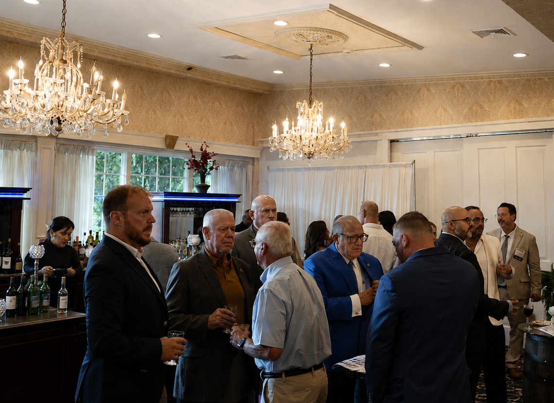 Guests networking with drinks at the bar beneath crystal chandeliers