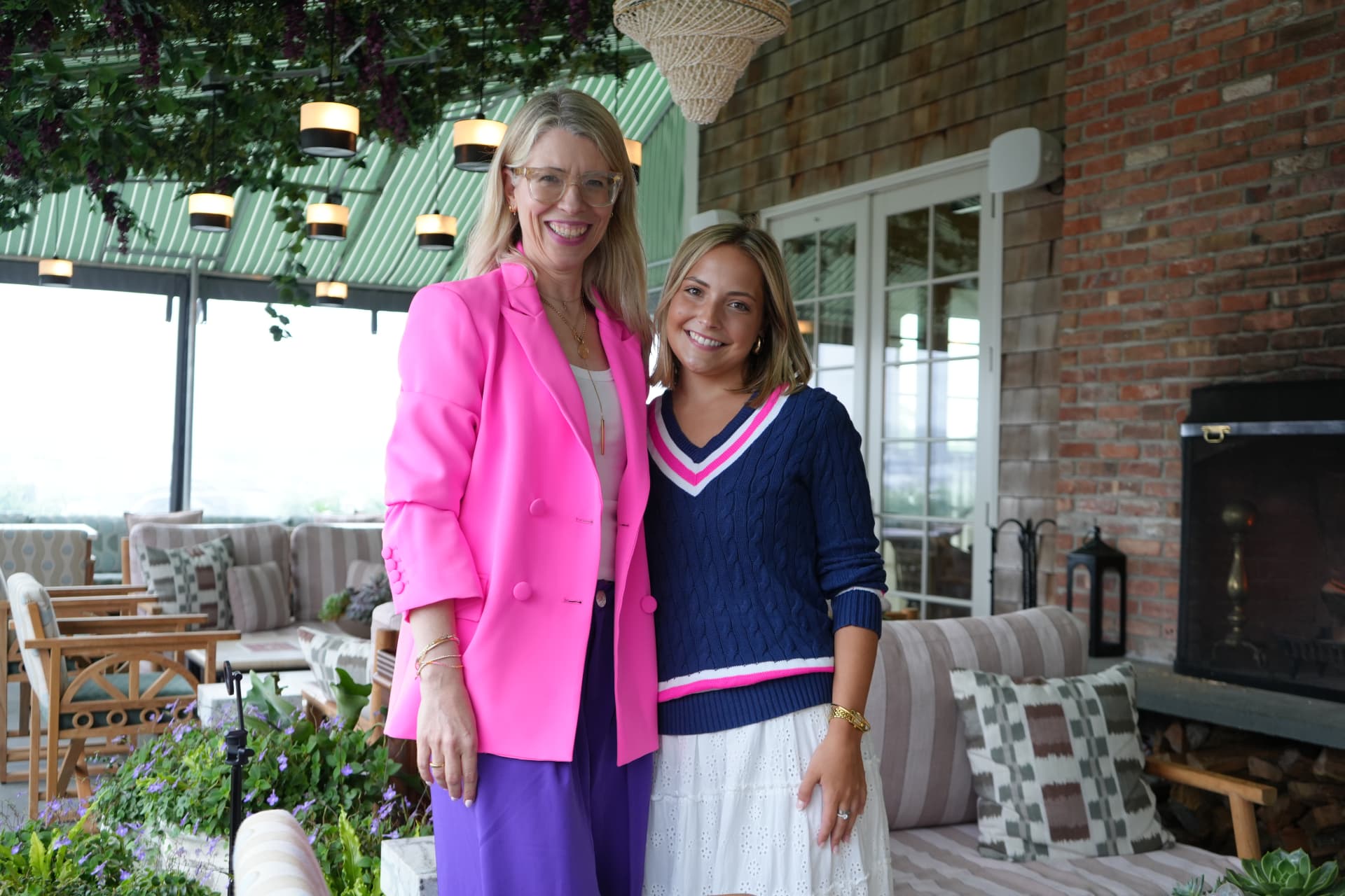 Two guests portrait beside the brick fireplace in the covered terrace lounge