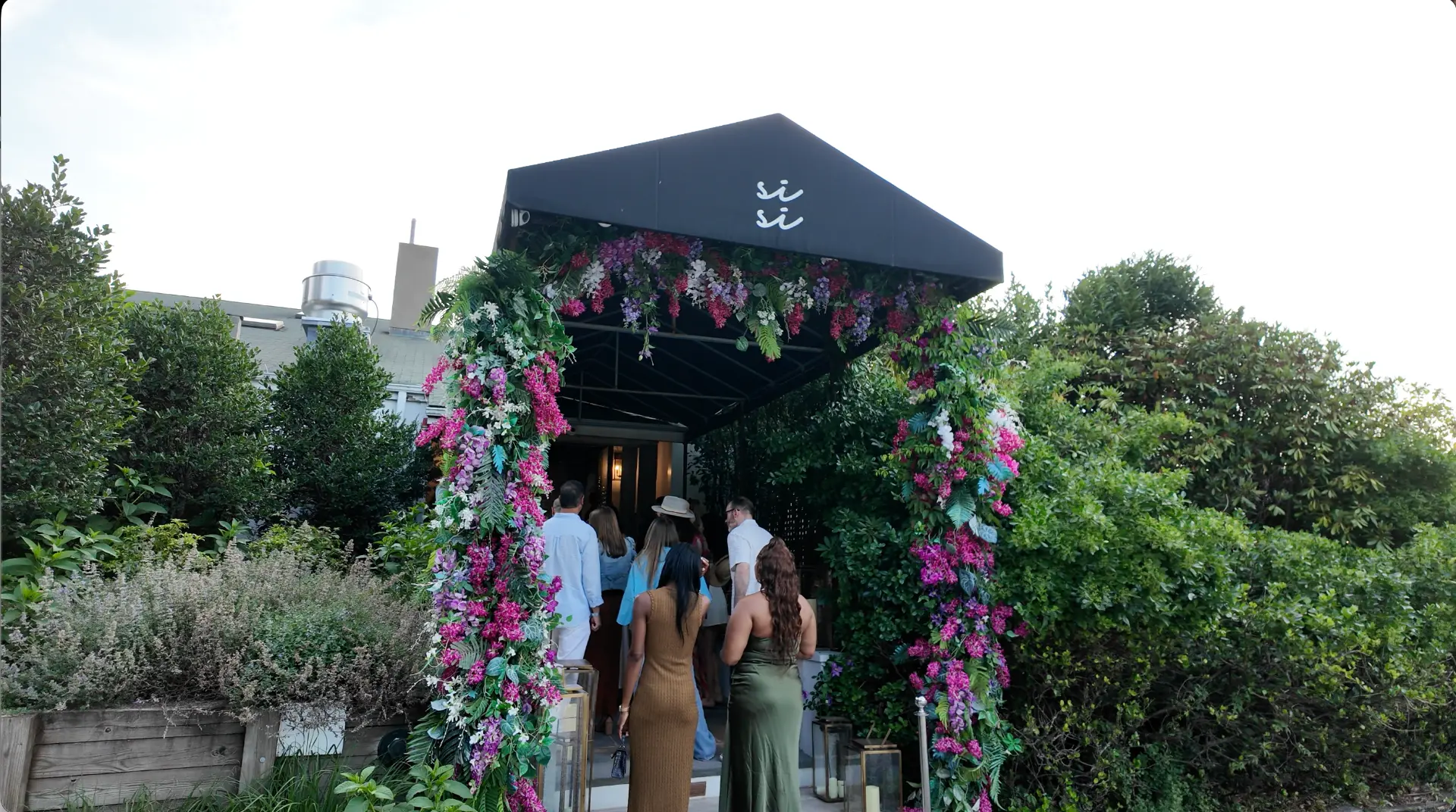 Guests arriving through the floral archway at the Si Si entrance