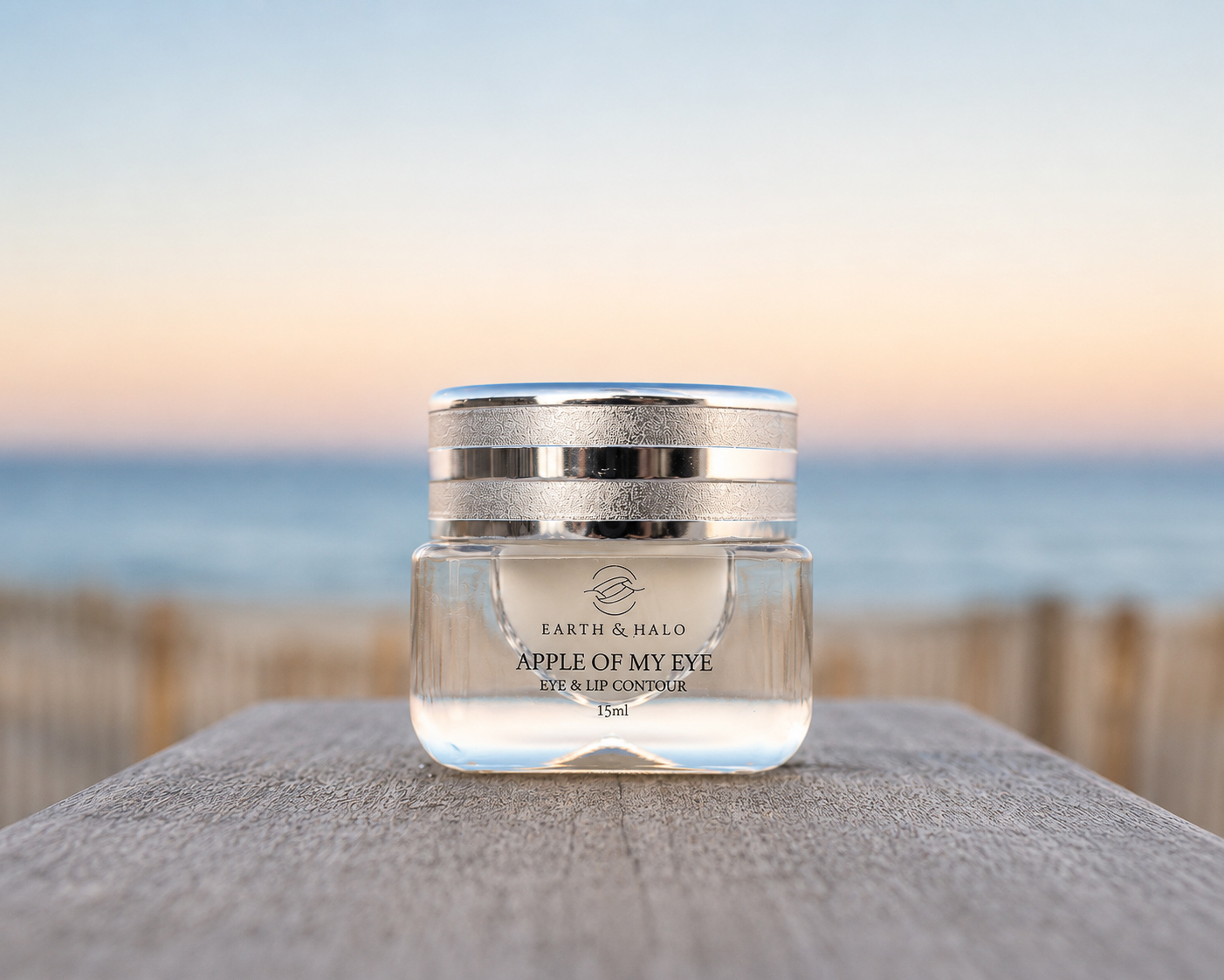 Earth & Halo eye and lip contour jar photographed at dusk beside the ocean