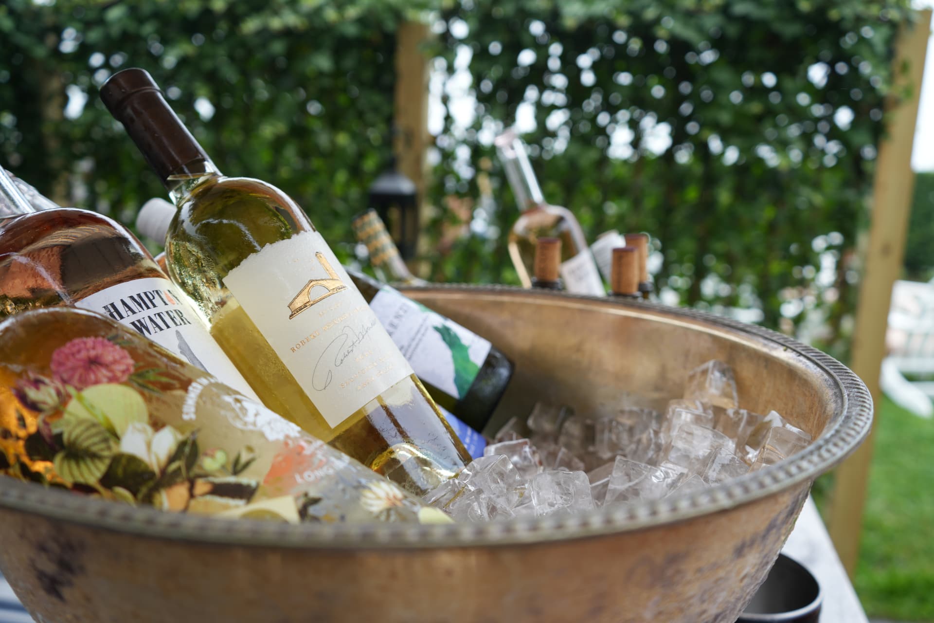 Chilled rosé and white wine bottles resting on ice in a hammered copper basin