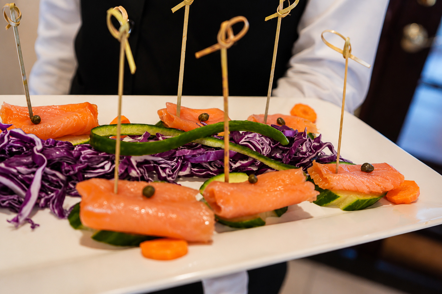 Server presenting a tray of smoked salmon canapés during the reception