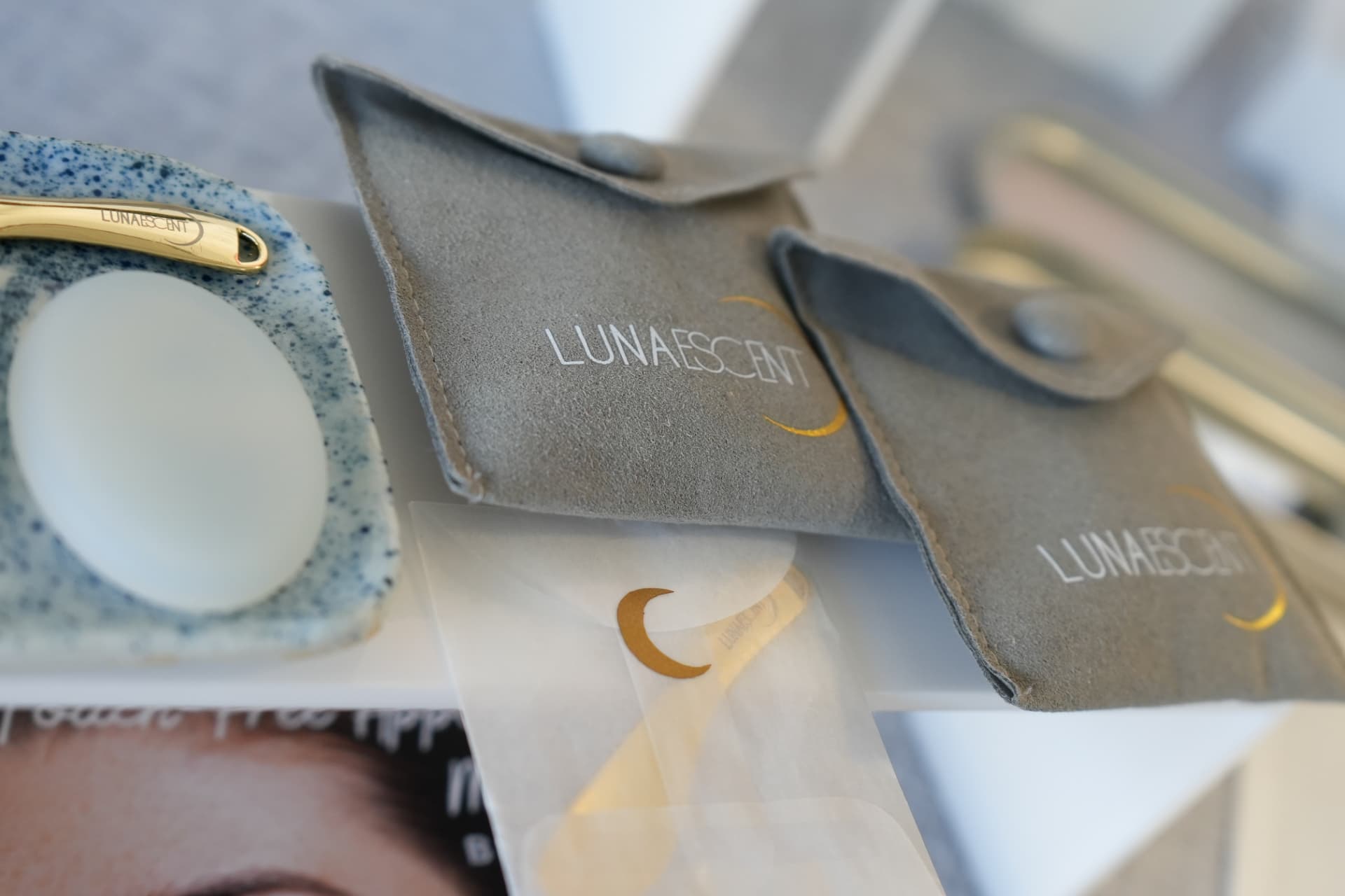 Suede product pouches and a gold-handled skincare tool on display