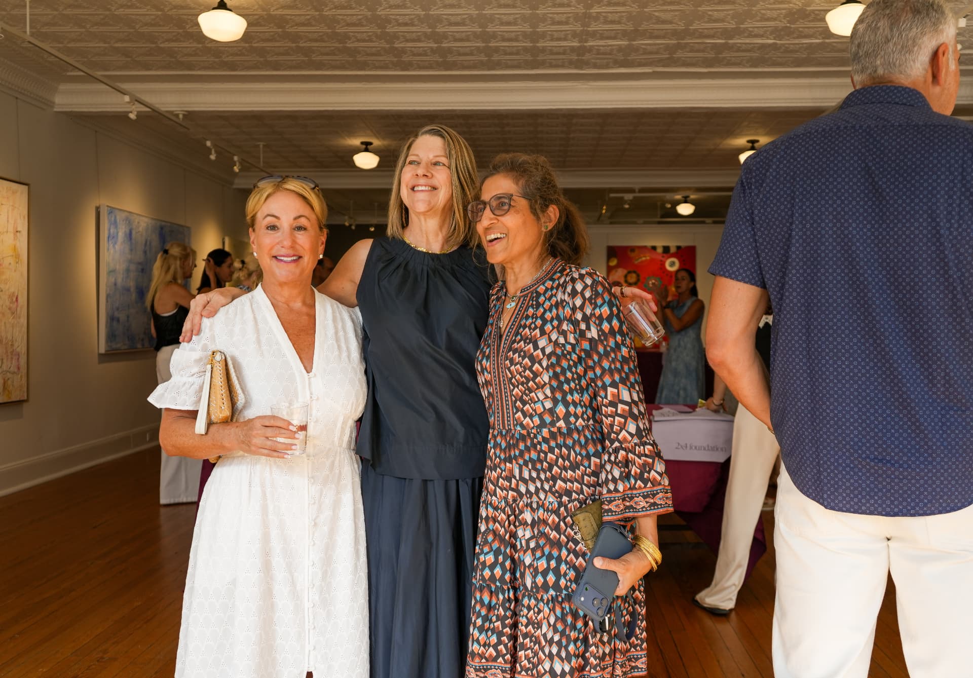 Three guests smiling together during the gallery reception