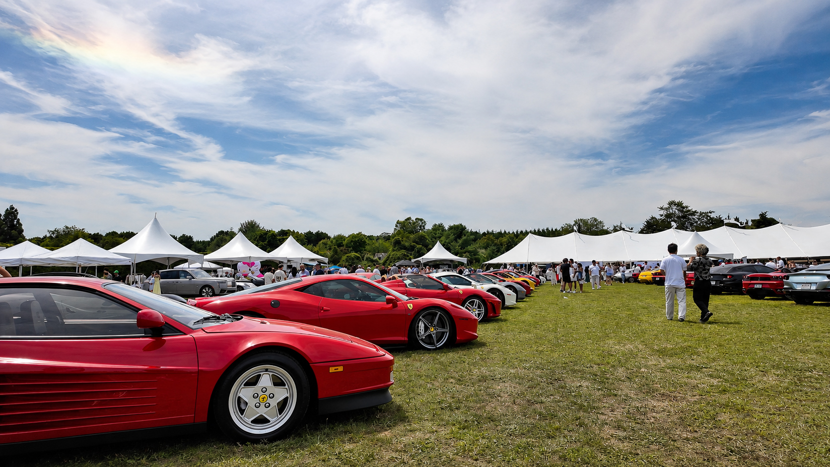Row of red Ferraris on the lawn beneath white tents in Bridgehampton